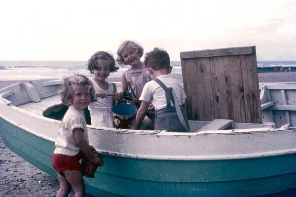 Four children on a beach, playing with a boat