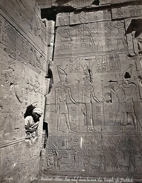 EGYPT: MEDINET HABU. A young man looking through a hole in a wall covered with