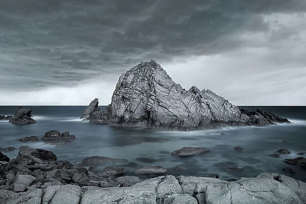 Large Coastal Rock Feature Against Dramatic Skies