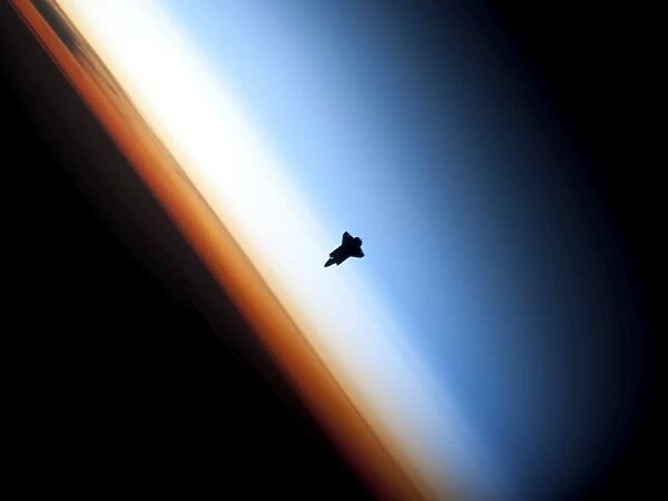 Silhouette of space shuttle Endeavour over Earths colorful horizon