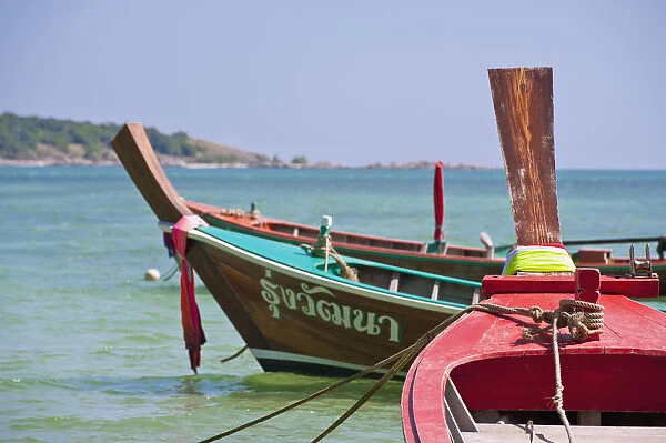 Thailand, Phuket, Rawaii Beach, Close up of longtail boats along the shoreline, Land in distance