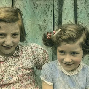 Delightful colour photograph of two little girls, possibly sisters, seated together