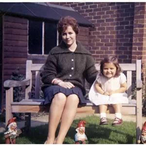 Young woman and her young niece on arden bench with gnomes