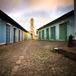 Deserted cobbled street looking towards the bell tower of the Inglesia y Convento de San Francisco off Plaza Major, Trinidad, Cuba, West Indies
