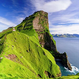 Kallur lighthouse on cliffs covered with grass with Borgarin mountain peak on background, Kalsoy island, Faroe Islands, Denmark, Europe