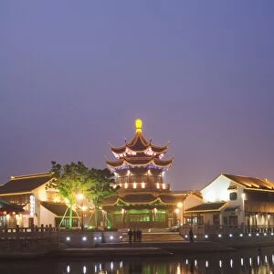 Traditional old riverside houses and pagoda illuminated at night in Shantang water town