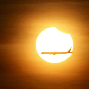 An aeroplane flies past the sun as it goes into a partial solar eclipse in Singapore