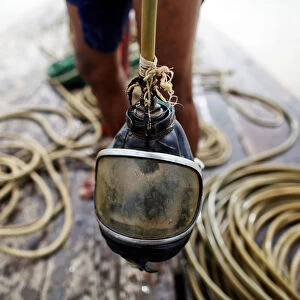 A diver holds his mask on a small boat on Yangon River after searching for coal