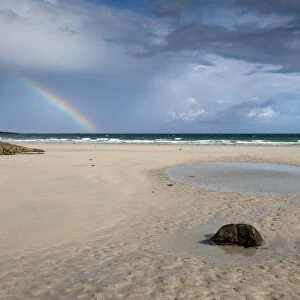 View of beach and rainbow forming over sea, Crossapol, Isle of Tiree, Inner Hebrides, Scotland, August