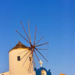 Church bell tower and windmill on the coast of Aegean Sea. Oia, Santorini Island, Greece