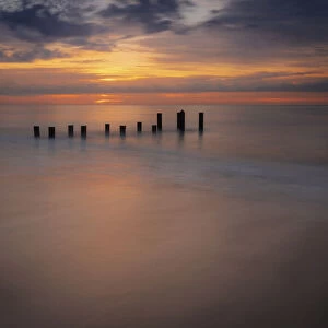 USA, New Jersey, Cape May National Seashore. Sunrise on pier posts on ocean shore