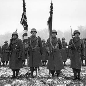 Color guards and color bearers of the Japanese-American 442nd Combat Team stand at attention at Bruyeres, France, on a battlefield where many of their comrades were killed. Photograph, 12 November 1944