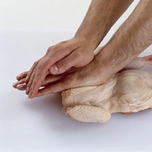 Using palm of hand and pressure from hand on top to flatten chicken breast