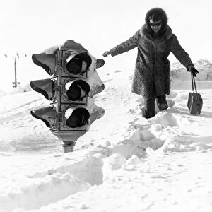 A woman walking by a traffic light on a huge snow drift after a five-day blizzard in yuzhno-sakhalinsk in the southern part of the soviet island of sakhalin, february 1970