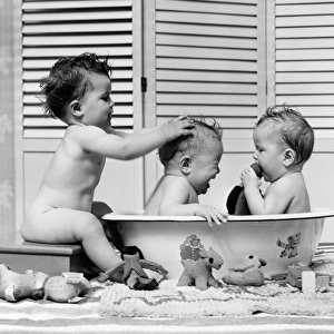 Three babies in wash tub, bathing
