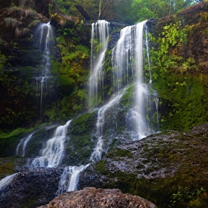 Cascading waterfall over green rocks