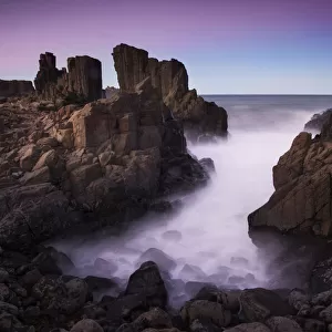 Motion blurred dreamy waves breaking on dramatic coastal basalt columns rock formations