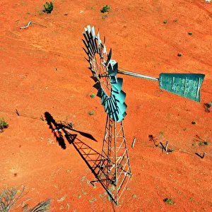 Windmill, water windpump on farm with dry red dirt field, Australia, aerial view