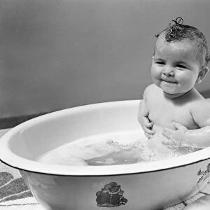 Baby sitting in bath, smiling. (Photo by H. Armstrong Roberts / Retrofile / Getty Images)