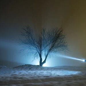 Silhouette of a person walking with a suitcase and a lantern, for a covered way of snow and fog during the night