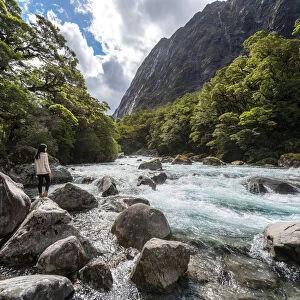 The women stands on a stone in the midst of watercourse with mountains in Milford highway