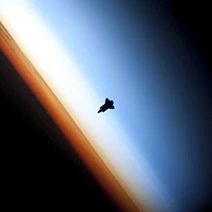 Silhouette of space shuttle Endeavour over Earths colorful horizon