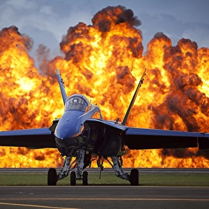 A wall of fire erupts behind a U. S. Navy F / A-18 Hornet aircraft