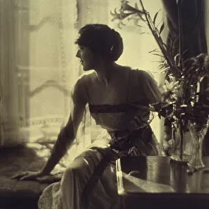 Woman sitting on window seat, looking left, full-length portrait, between 1900 and 1920. Creator: Unknown