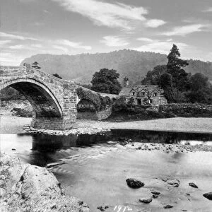 A Stereoview image of Llanrwst Bridge. The three spans of Pont Fawr rise elegantly over the River Conwy. Its central arch had the largest span in Wales when built. The bridges design is popularly attributed to architect Inigo Jones (1573-1652), Now a Scheduled Ancient Monument and Grade I listed building, it remains in continual use. The present bridge was completed in 1636. This picture from 1872. A manor house dating from 1492, the 15th-century courthouse known as Tu Hwnt i r Bont