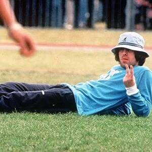 Liam Gallagher of pop group Oasis gives the v sign as he lies on the grass during a